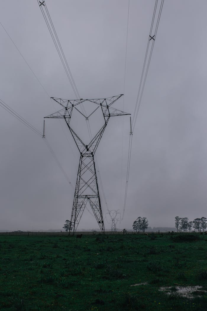 about-03 A tall electric transmission tower stands amidst fog, capturing the essence of industrial nature.